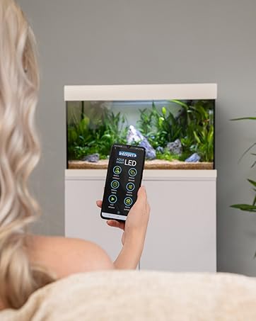 lifestyle image woman using smart phone app with aquarium in backgound